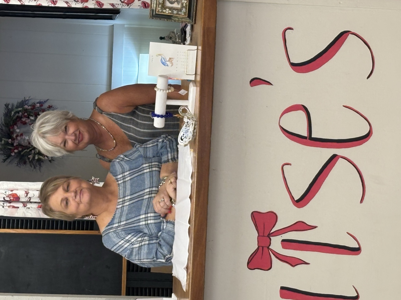 Lou and Pam behind the counter, under the painted Louise's bow