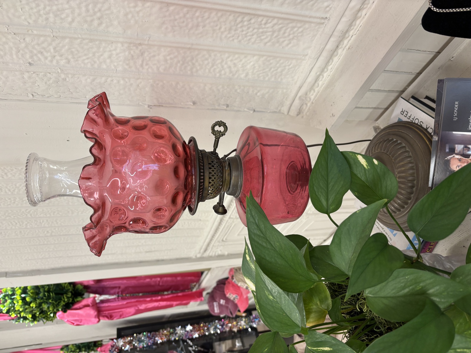 Louise Lankford's cranberry-pink glass lamp displayed beside greenery